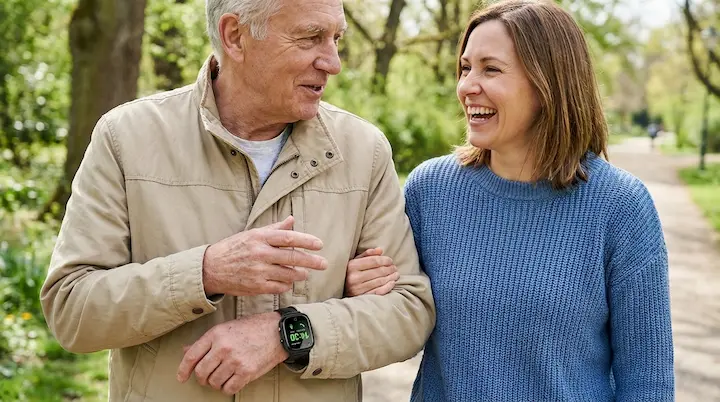 Senior father and adult daughter together outdoors, smiling